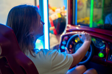 Woman playing racing simulator game in theme park.