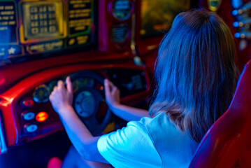 Woman playing racing simulator game in theme park. - obrazy, fototapety, plakaty