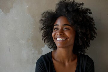 Portrait of a joyful young woman with curly hair smiling against a neutral background.