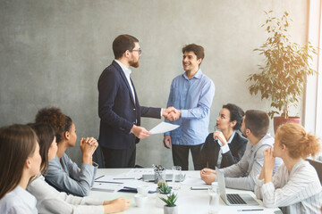 Two businessmen shaking hands at meeting in modern office