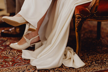 Les jambes de la mariée dans sa robe blanche pendant la cérémonie religieuse - obrazy, fototapety, plakaty