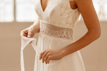 Mariée dans sa robe blanche ajustant sa ceinture - 773387309