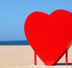 Red heart sculpture at a beach with blue sky stands for love beaches