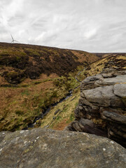 Fields, hills, mountains and a large rock in the foreground. Yorkshire moors. Wild and bleak. Rocky hill top scenic view at dusk