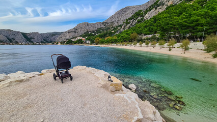 Baby stroller on idyllic sand beach Plaza Brzet in coastal town Omis, Split-Dalmatia, Croatia,...