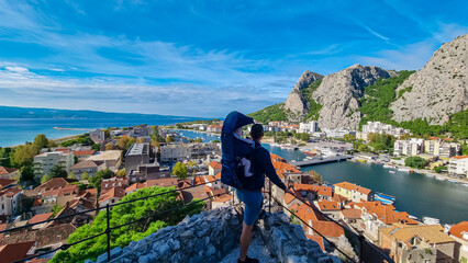 Father with baby carrier looking at coastal town Omis surrounded by Dinara mountains in...