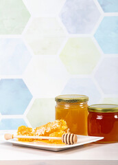 Glass honey jars with different color honey inside, lot of copy space on light blue honeycomb pattern background. Honey border background concept.