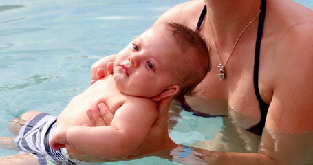 Mother and infant newborn baby at the swimming pool for the first time