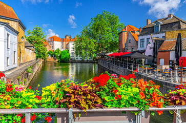 Naklejka premium Metal fence with flowers pots, Groenerei Green Canal with trees and plants, promenade embankment in Brugge old town district, medieval houses in Bruges city historical center, Flemish Region, Belgium
