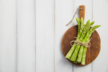 Bunch of fresh asparagus on wooden cutting board - 773404566