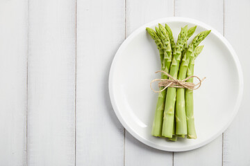 Bunch of fresh asparagus on white plate