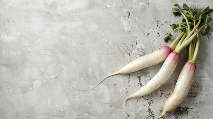 Bunch of white radishes with green leaves on grey textured background.
