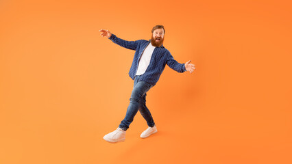 Fototapeta na wymiar Positive redhaired guy with beard fooling posing on orange background
