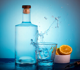 Spirits bottle and tumbler glass with ice and liquid splashing out of the glass.