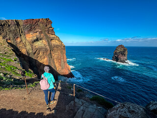 Hiker woman on idyllic hiking trail along rocky rugged cliffs at Ponta de Sao Lourenco peninsula,...