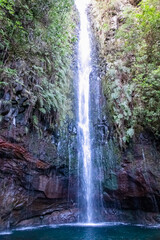 Obraz premium Scenic view of majestic waterfall Cascata das 25 Fontes along idyllic Levada walk in evergreen subtropical Laurissilva forest of Rabacal, Madeira island, Portugal, Europe. Clear plunge basin below