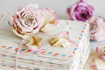 A stack of vintage love letters and a single rose flower lying on it.