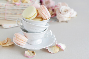 French macaroons in porcealin cup. Roses and love letters in the background.