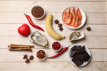 Natural aphrodisiac. Different food products and red decorative heart on light wooden table, flat...