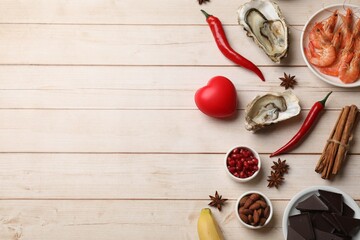 Natural aphrodisiac. Different food products and red decorative heart on light wooden table, flat...