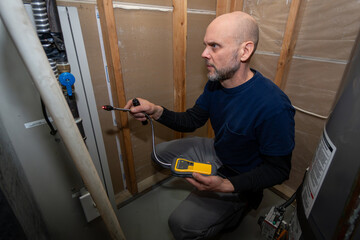 Home Inspector searching and using UEFI carbon monoxide detector to test basement gas furnace.