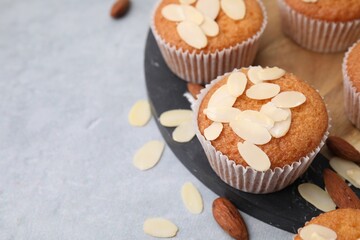 Muffins with fresh almond flakes and nuts on grey table, closeup. Space for text