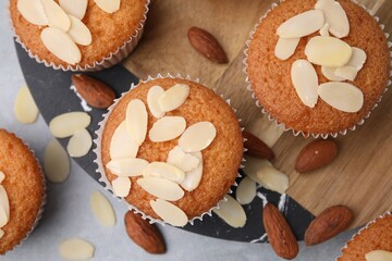 Muffins with fresh almond flakes and nuts on grey table, flat lay