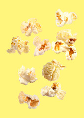 Tasty fresh popcorn flying on yellow background