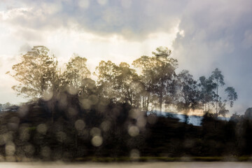 A lake landscape seen through a window with a defocused raindrops, in the afternoon in the eastern Andean mountains of central Colombia.