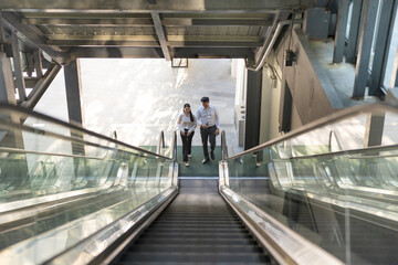 Two professionals in conversation while riding an escalator