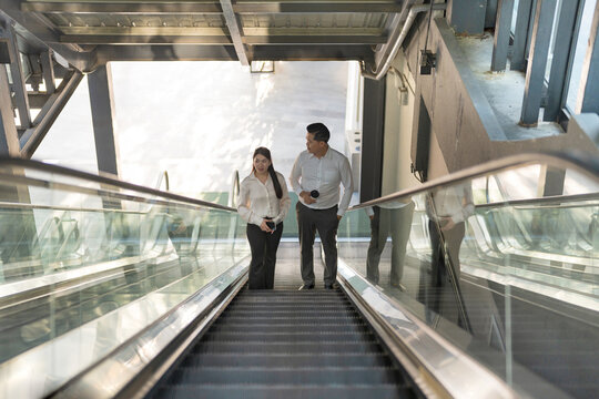 Two professionals in conversation while riding an escalator