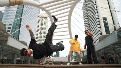 Group of professional street dancer cheer up while asian hipster perform freestyle footstep at city...