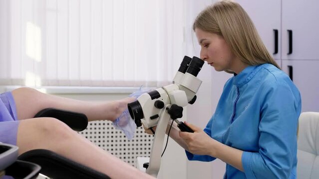 Gynecological office in the clinic. A gynecologist uses a colposcope to examine a patient. A woman lies on a gynecological chair during a colposcopy. Preparing for pregnancy. Modern hospital.