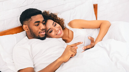 Couple in bed watching content on smartphone