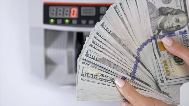 A female holds one hundred dollar dollars.
