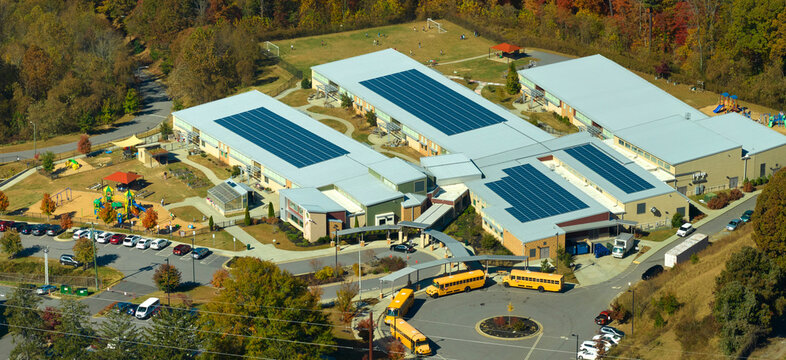 Roof of american school building covered with photovoltaic solar panels for production of electric energy. Renewable energy concept