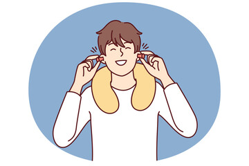 Happy man uses earplugs and neck pillow to rest during long journey on bus or plane. Positive guy traveler is in good mood after getting enough sleep on train
