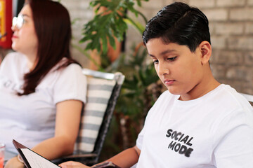 Niño latinoamericano leyendo revisando el menu - obrazy, fototapety, plakaty