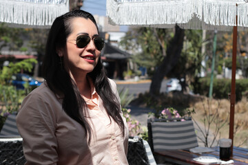 Mujer latina sentada en una silla con sombrillas al aire libre