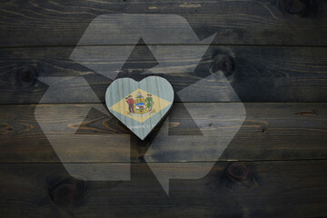 wooden heart with national flag of delaware state near reduce, reuse and recycle sing on the wooden...