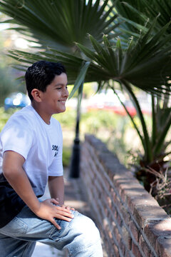 Ni&ntilde;o latinoamericano feliz recargado de una barda al aire libre