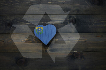 wooden heart with national flag of nevada state near reduce, reuse and recycle sing on the wooden background. concept