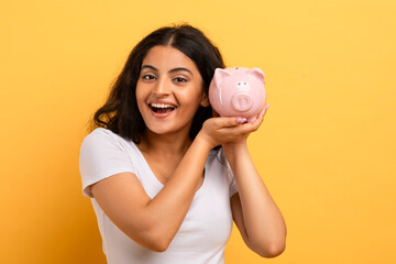Woman holding a piggy bank with a beaming smile