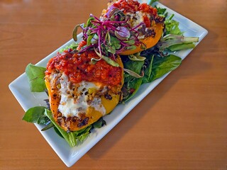 Stuffed bell peppers garnished with lettuce on a white appetizer plate 