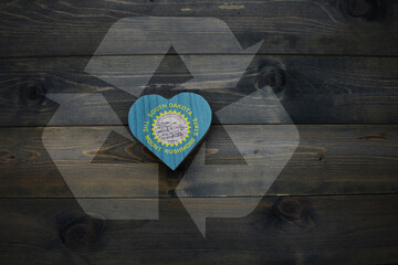 wooden heart with national flag of south dakota state near reduce, reuse and recycle sing on the...