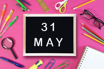 May 31 written in chalk on black board. Calendar date 31th of May on chalkboard on pink blurred school stationery background. Event schedule date. School, study, education concept. Month of spring. - obrazy, fototapety, plakaty