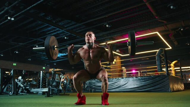 A strong male bodybuilder with impressive muscles doing barbell squats, demonstrating power and endurance in a contemporary fitness center with advanced equipment. Camera 8K RAW. 