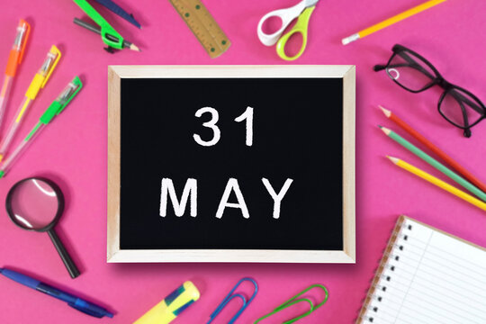 May 31 written in chalk on black board. Calendar date 31th of May on chalkboard on pink blurred school stationery background. Event schedule date. School, study, education concept. Month of spring.