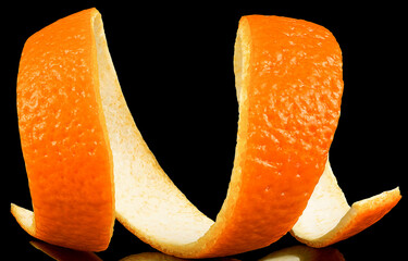 Fresh orange skin in spiral form on a black background. Citrus zest of orange fruit.