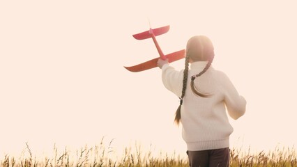 Girl with toy airplane runs across field. Child, kid plays with red plane, runs across meadow as if...